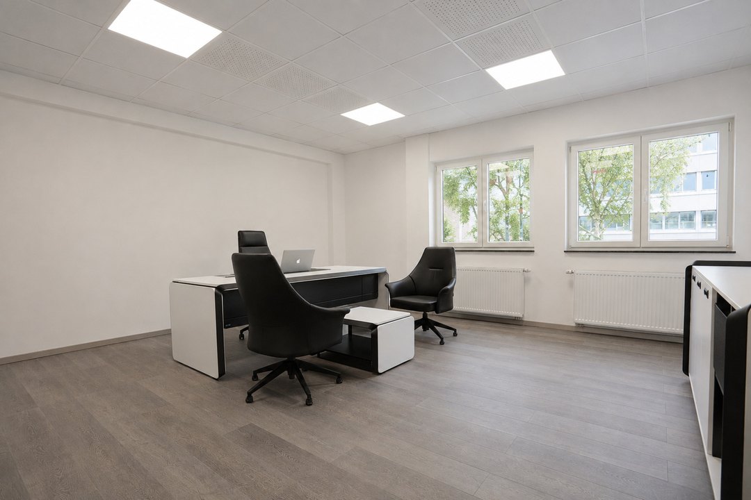 Büro mit Schreibtisch, Sesseln und zwei Fenstern zur begrünten Straßenseite