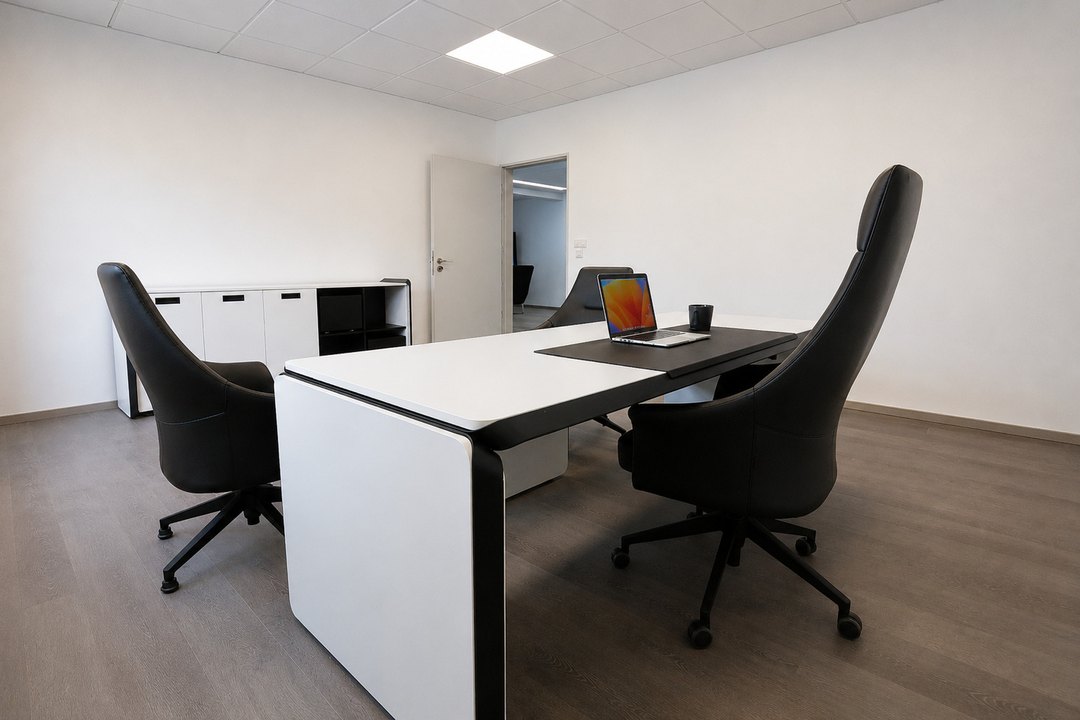 Arbeitsplatz mit Laptop, zwei Sesseln und Sideboards im Hintergrund