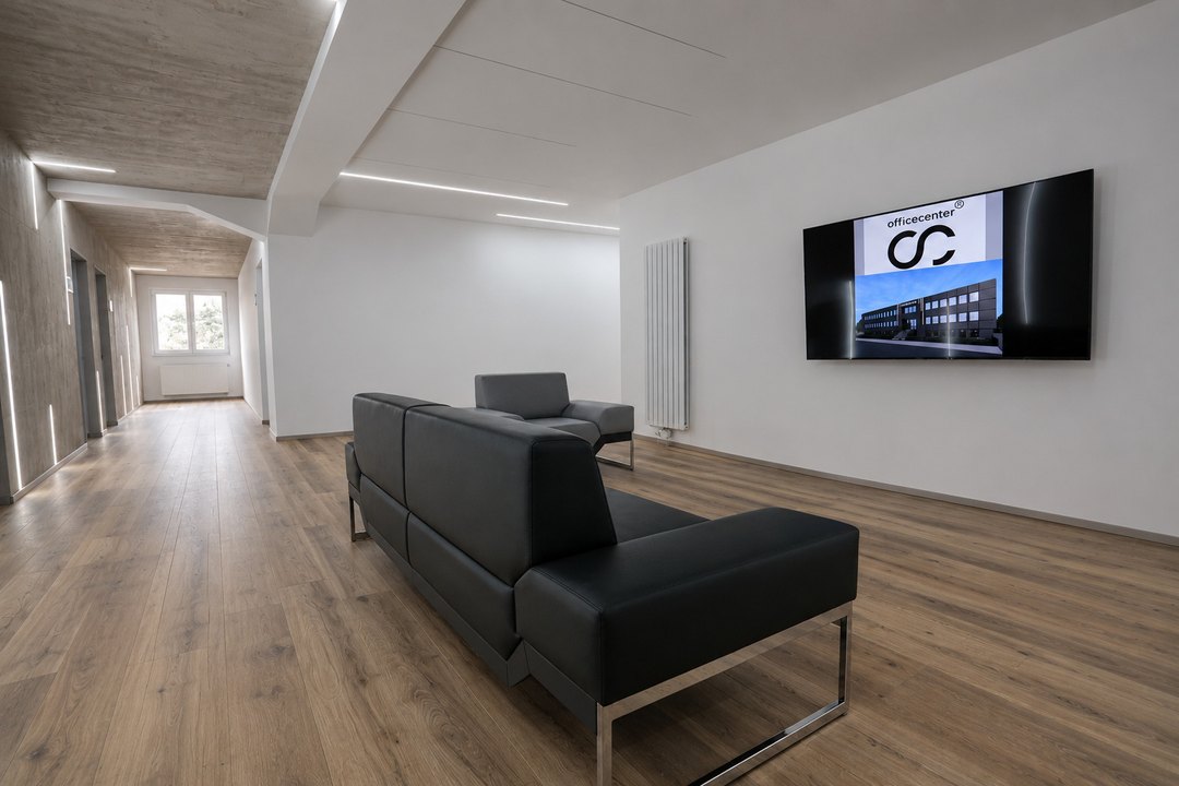 Wartebereich mit Ledersofa, Wandbildschirm und Blick in den Flur